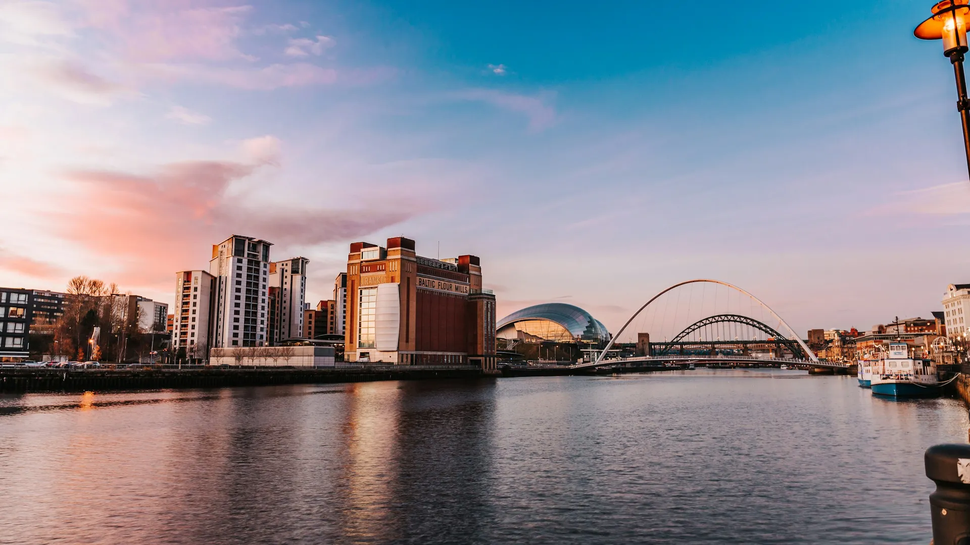 The Newcastle and Gateshead quayside at sunset, with the Sage Gateshead and the Gateshead Millennium Bridge on the River Tyne